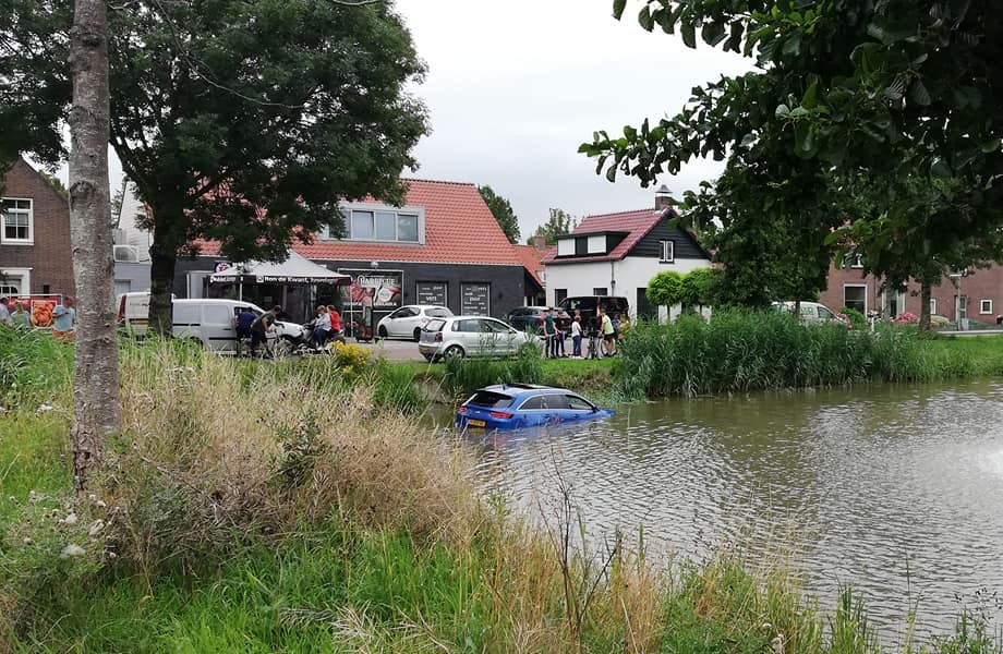 Auto te water in vijver aan Kerkstraat in Hank